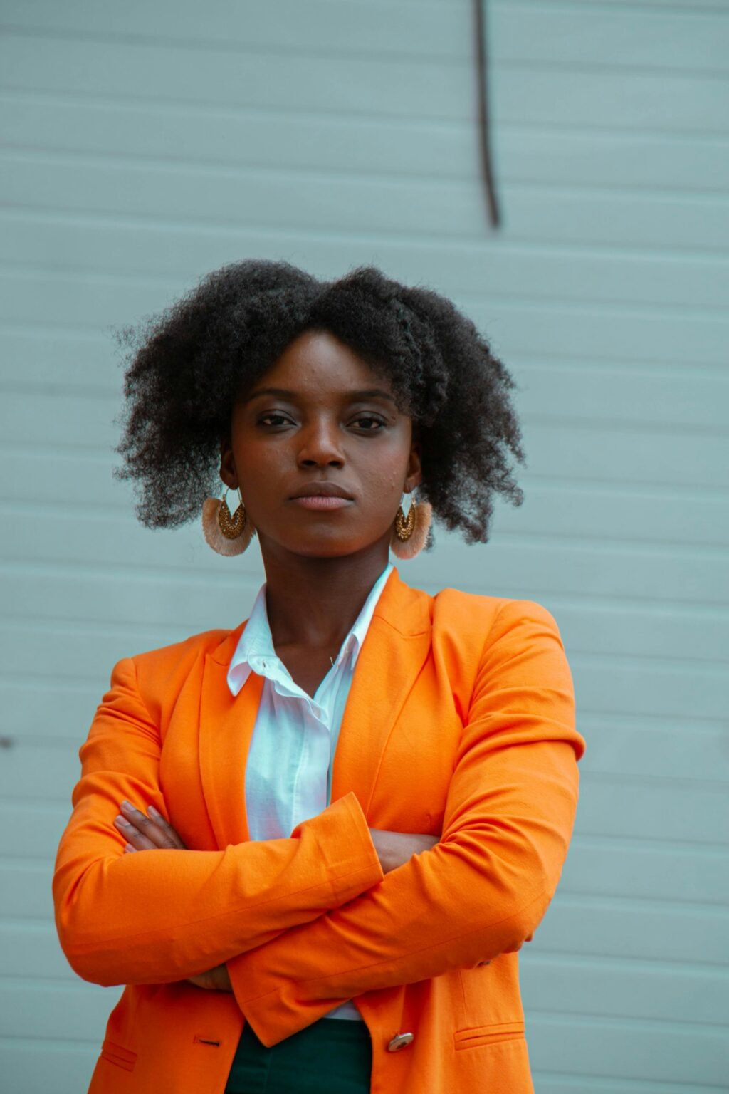 Founder in an orange blazer standing against a pale blue wall